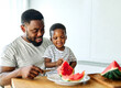 © Lumos sp - child family kitchen food boy son father watermelon fruit slice summer organic meal fun preparing healthy diet eating home black