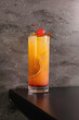 Cocktail alcolico all'arancia guarnito con fette di arancia affumicate e una ciliegia caramellata