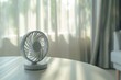 Closeup of a portable fan oscillating on a white table in a brightly lit room, showcasing a modern approach to air circulation