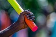 A runners hand tightly gripping a brightly colored baton during a relay race