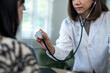 © Wasana - A woman doctor is holding a stethoscope and examining a patient