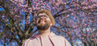 Banner Man allergic enjoying after treatment from seasonal allergy at spring. Portrait of happy bearded man smiling in front of blossom tree at springtime. Spring blooming and allergy concept. Copy