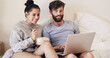 © peopleimages.com - Couple, laptop and smile in bed for popcorn, online and streaming in apartment, relax and watch of show. Weekend, home and hungry for food, man and woman with computer for video, bonding and love