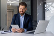 © Tetiana - Businessman using tablet in a modern office setting