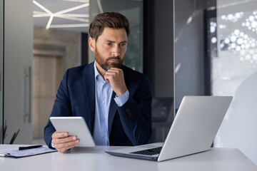 Focused businessman analyzing data on laptop in modern office