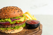 Burger with delicious patty, french fries and sauce on light table, closeup