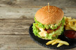 Burger with delicious patty, french fries and sauce on wooden table, space for text