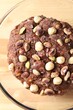 Raw chocolate dough with nuts in bowl on wooden table, top view