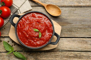 Wall Mural - Homemade tomato sauce in bowl, spoon and fresh ingredients on wooden table, flat lay. Space for text
