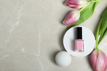 Wall Mural - Flat lay composition with pink nail polish in bottle and tulip flowers on light textured table. Space for text