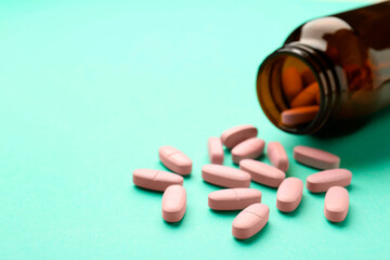 Sticker - Vitamin pills and bottle on mint color background, closeup. Space for text