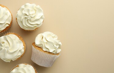 Poster - Tasty vanilla cupcakes with cream on beige background, top view. Space for text