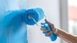 Closeup of a Hand Holding a Painter Roller with Blue Paint Painting a White Wall for Home