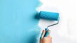 Roller in Hand Painting Blue on White Wall for Home Interior Renovation and Decor