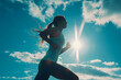 Silhouette of a Female Runner Against the Sun and Blue Sky