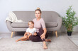 Blonde cheerful woman sitting on floor with her daughter looking at camera, having sport training together, family sitting on floor at home, fitness workout with child.
