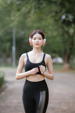 Fototapeta  - Beautiful Asian female runner doing morning exercise outdoors in city park. smile happily Exercise for good health