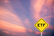 Yellow transportation sign with word ETF (abbreviation of Exchange Traded Fund) on violet color sky background