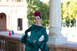 Beautiful young woman with typical green frilly dress and dancing flamenco in plaza de espana in sevilla, andalusia, she is on a balcony of the famous square. 16 november, international flamenco day.