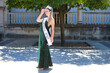 Pretty young woman winner of a beauty pageant dressed in a green sequined dress. Young woman wears diamond crown and winner's sash and poses for photo. Fashion and beauty concept.