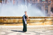 Young and beautiful woman winner of a beauty contest dressed elegant and wearing a crown of diamonds, is in sevilla in the famous plaza de espana in front of the central fountain between soap bubbles.