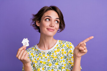 Sticker - Photo of pretty young woman hold small house point finger empty space wear t-shirt isolated on violet color background