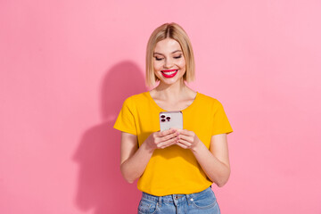 Wall Mural - Photo of cheerful positive lady dressed yellow t-shirt communicating modern device isolated pink color background