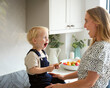 Mother With Young Son At Home In Kitchen Eating Cookie