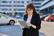 Mature woman manager agent using digital tablet for work, city background