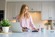 Smiling Woman Working From Home In Kitchen Using Laptop