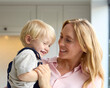Loving Mother Cuddling Young Son At Home In Kitchen Together
