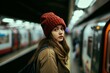 Portrait of a thoughtful young woman wearing a red beanie, waiting for the train at a subway station