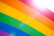 LGBT Pride Month rainbow texture concept. LGBTQIA colorful background with rainbow freedom flag and real sun flare, selective focus.