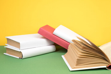 Sticker - Books stacking. Open hardback books on wooden table and green background. Back to school. Copy space for ad text.