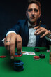 Poker player with cards and chips at green table in casino.