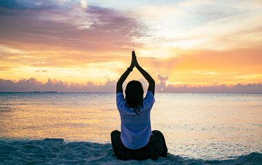 Wall Mural - woman doing yoga at sunset on tropical beach