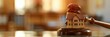 A small wooden gavel and miniature model of an apartment building on a table with a blurred background