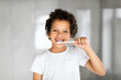 © Prostock-studio - African American young boy with short hair is diligently brushing his teeth with a blue toothbrush in front of a mirror. He is standing in a bathroom, focused on his oral hygiene routine.