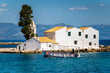 Kloster Vlacherna auf Korfu nahe der Landebahn des Flughafens mit davor fahrendem Boot