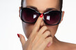 Stylish woman adjusts large sunglasses with a touch of elegance, perfect for summer fashion