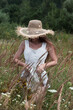 Young sexy beautiful woman in a straw hat is standing in a field.	