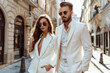Portrait of stylish beautiful woman and man in suit in the city, modern young couple on city street