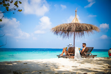 Wall Mural - couple relaxing on tropical beach chairs