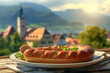 White sausage on a plate on a restaurant table outdoors with a Bavarian town in the background