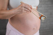 A pregnant woman holds a roll with chopsticks. Close-up of the belly.