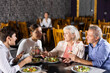 © JackF - Elderly couple and young couple chatting and enjoying dinner in restaurant