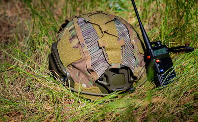 Wall Mural - A helmet, and a walkie-talkie on the ground on a sunny day. Military equipment, military protection. 