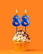Blue candle number 88 - Birthday cupcake on orange background