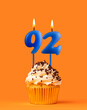 Blue candle number 92 - Birthday cupcake on orange background