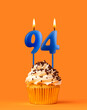 Blue candle number 94 - Birthday cupcake on orange background